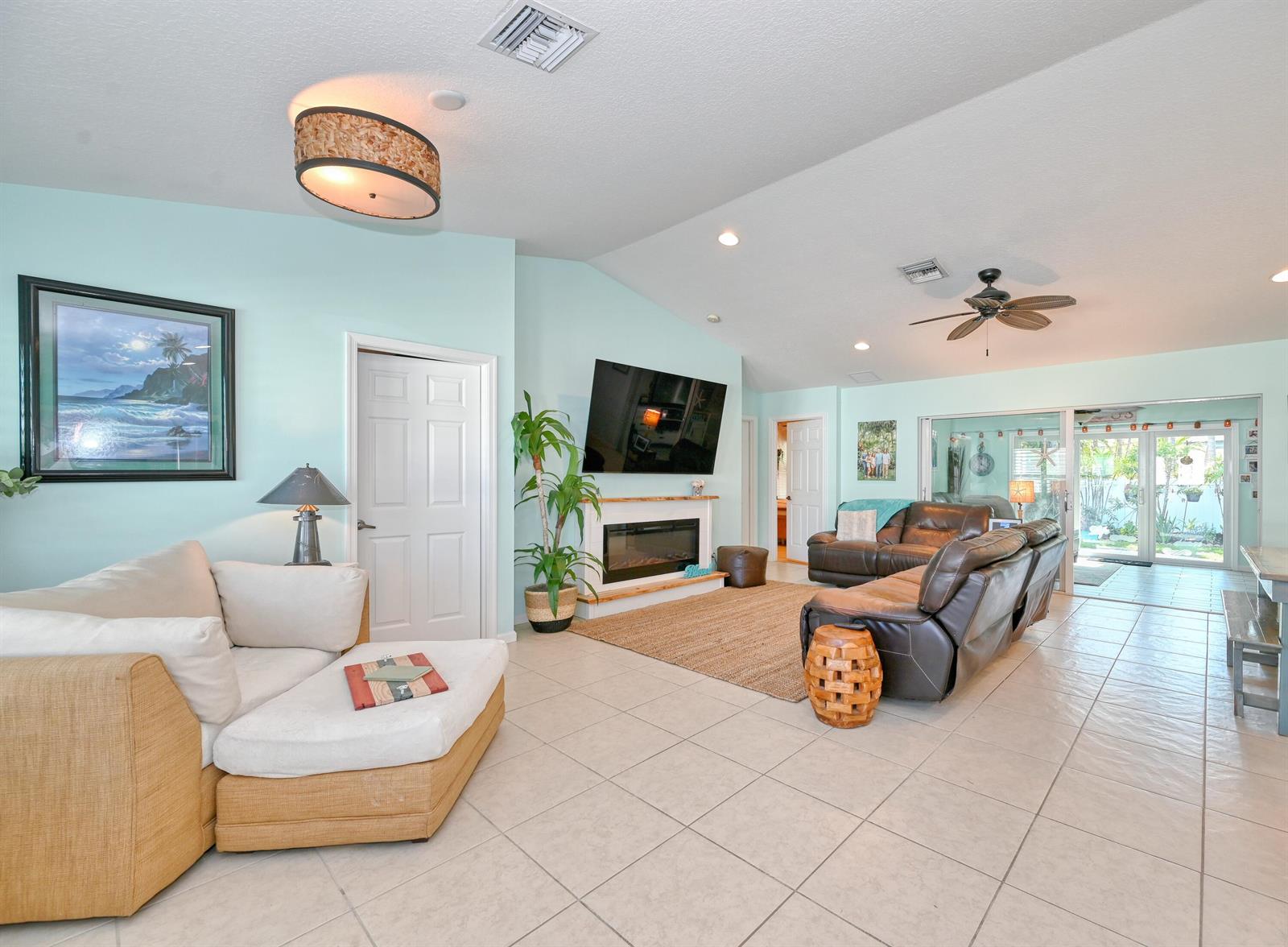 A living room features light blue walls, tile flooring, a fireplace, and two seating areas — 126 Faith Way, Jupiter FL 33458, JUPITER, FL