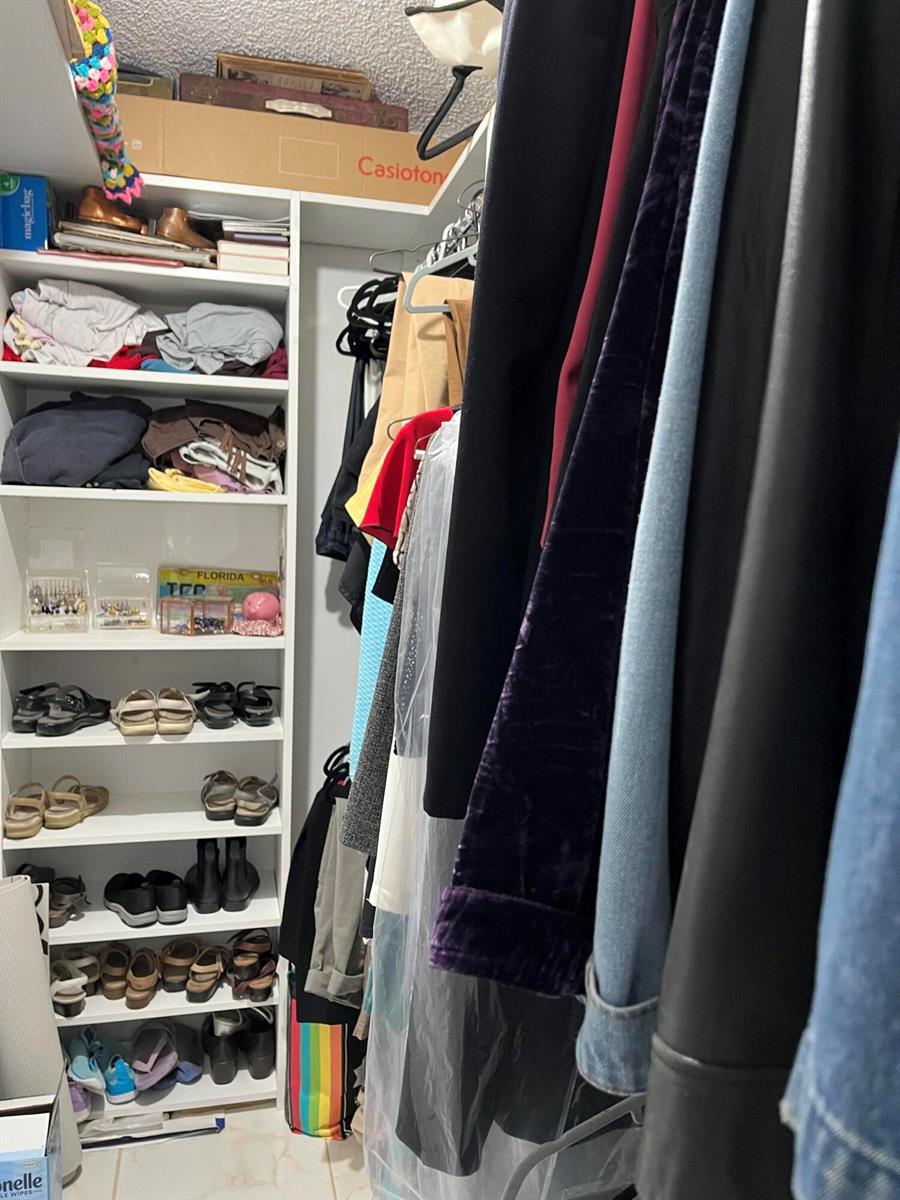 A walk-in closet features white shelving units filled with folded clothes and shoes — 358 Burgundy H, Delray Beach FL 33484, DELRAY BEACH, FL