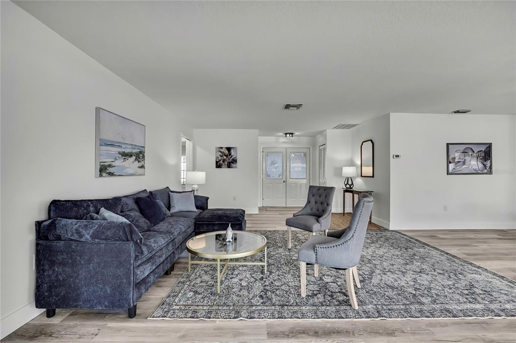 A living room features a dark blue sectional sofa, two gray chairs, and a round table — 7231 BIG BEND DRIVE, SPRING HILL, FL