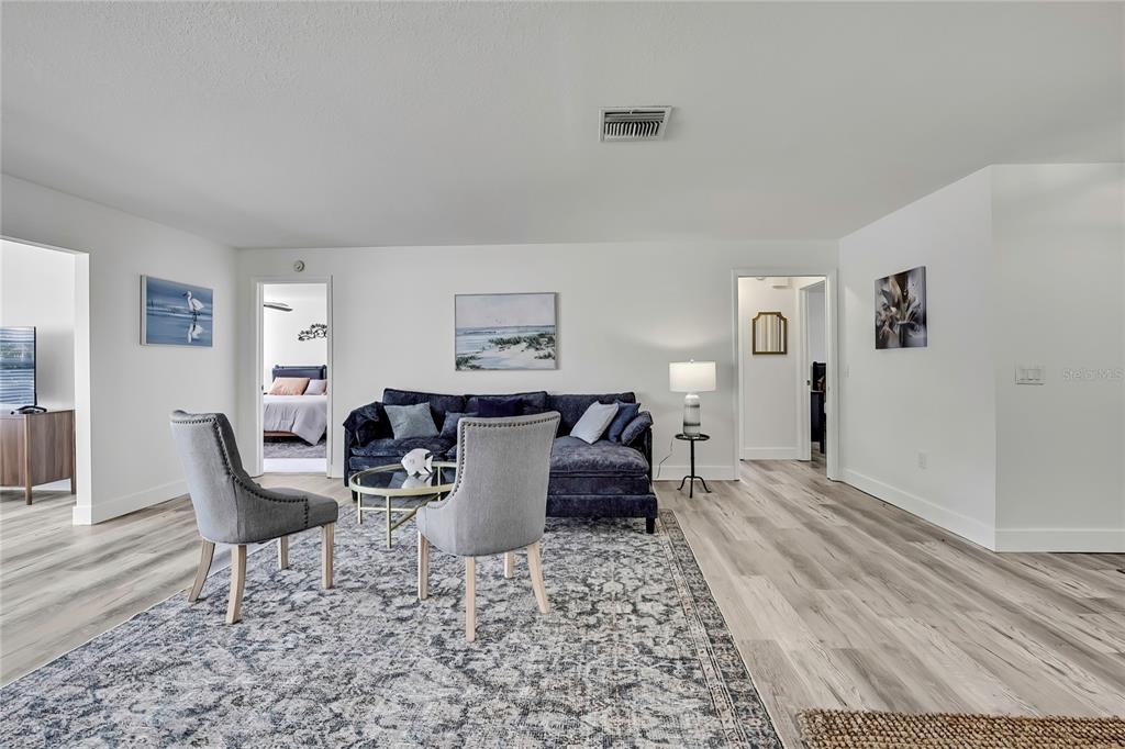 A living room features a dark blue sectional sofa, two gray chairs, and light wood flooring — 7231 BIG BEND DRIVE, SPRING HILL, FL