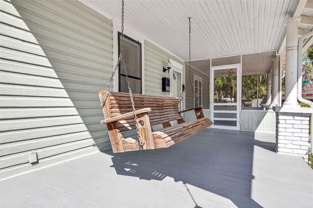 A wooden porch swing hangs on a covered front porch with light green siding — 630 NE 6TH AVENUE, GAINESVILLE, FL