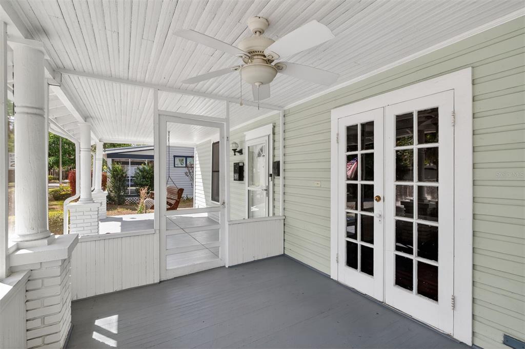 A covered porch features a ceiling fan, gray painted flooring, and white French doors — 630 NE 6TH AVENUE, GAINESVILLE, FL