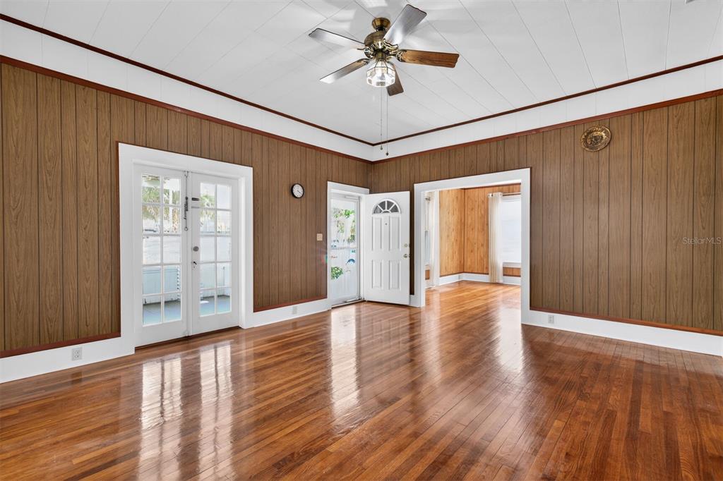 A room with wood-paneled walls, hardwood floors, a ceiling fan, and multiple doorways — 630 NE 6TH AVENUE, GAINESVILLE, FL