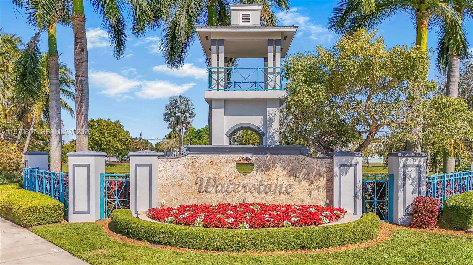 The entrance sign for Waterstone features a stone wall, red flowers, and a tall tower — 3736 NE 9 CT, Homestead FL 33033, HOMESTEAD, FL