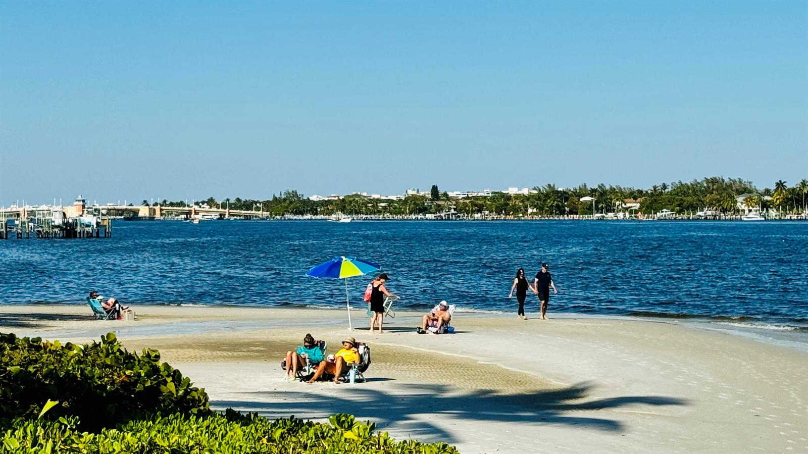 People relax on a sandy beach with a blue umbrella near a calm bay — 7030 Half Moon Circle # 121, Hypoluxo FL 33462, HYPOLUXO, FL