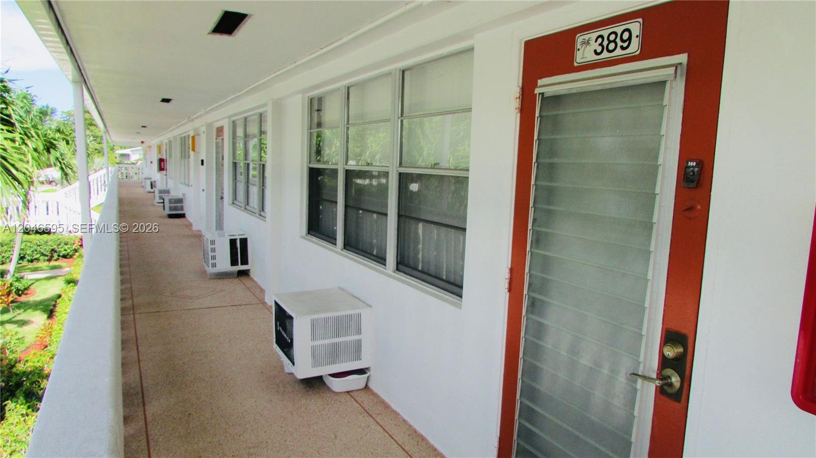 An exterior walkway features a row of apartment doors with louvered windows and air conditioning units — 389 Tilford R # 389, Deerfield Beach FL 33442, DEERFIELD BEACH, FL