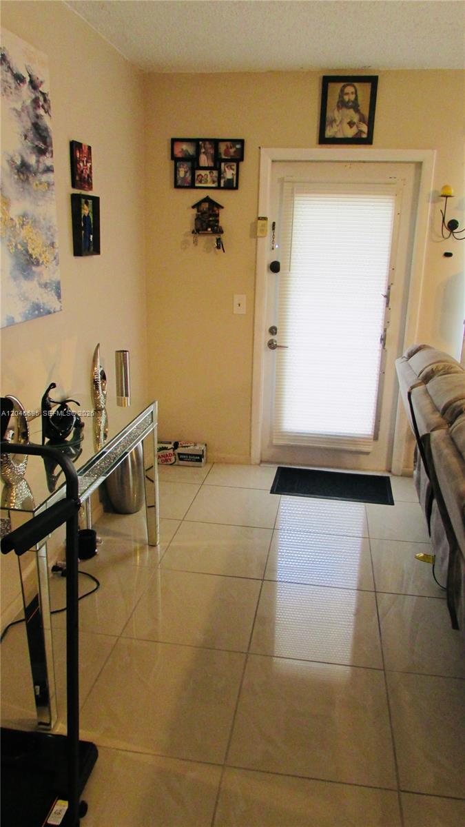 An entryway features light-colored tile flooring, a glass-topped console table, and a white front door — 389 Tilford R # 389, Deerfield Beach FL 33442, DEERFIELD BEACH, FL