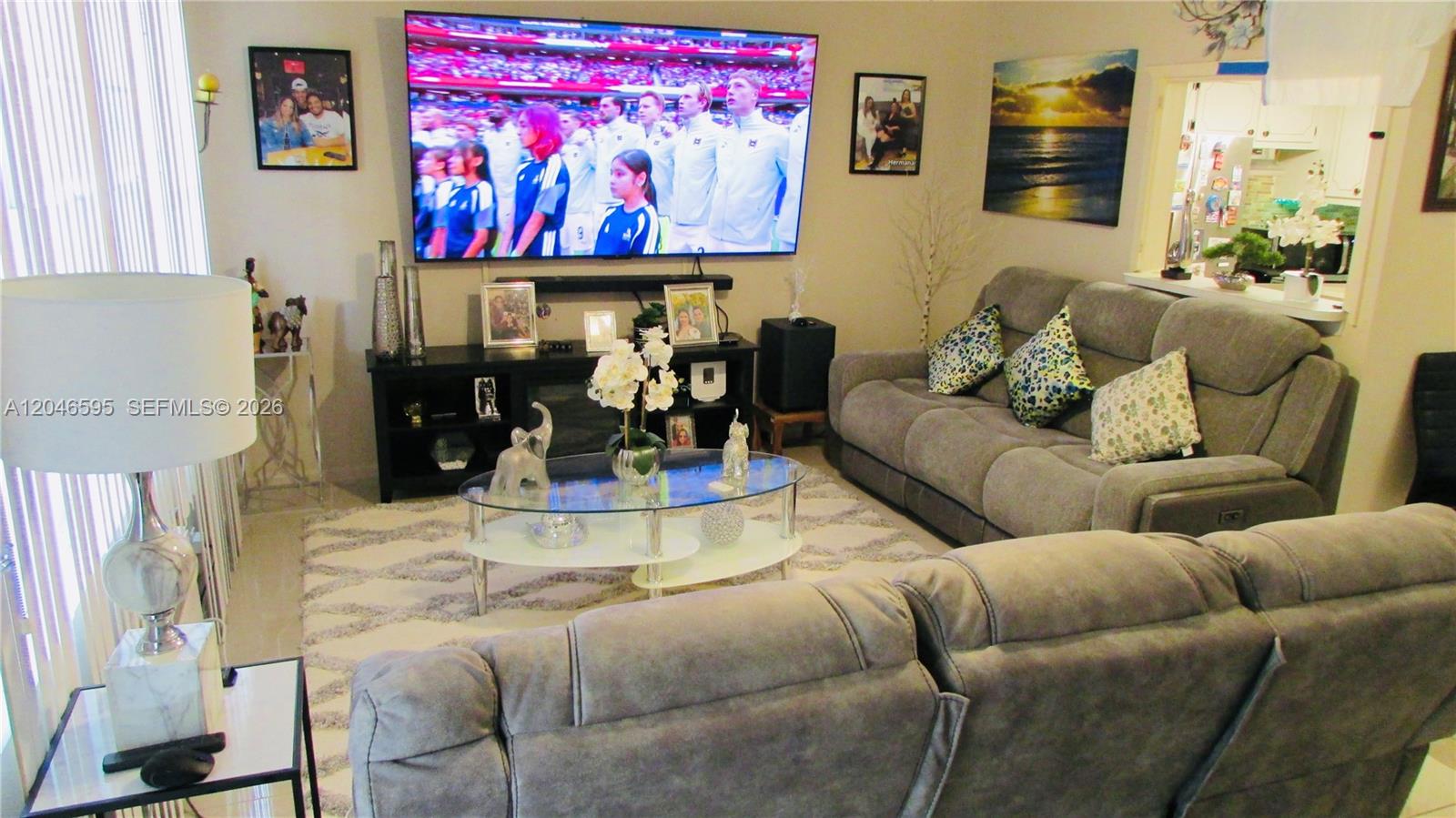A living room features a large television, gray sofas, and a glass-topped coffee table — 389 Tilford R # 389, Deerfield Beach FL 33442, DEERFIELD BEACH, FL