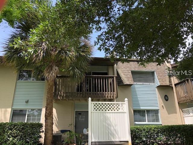 A two-story apartment building exterior features a wooden balcony, light blue siding, and palm trees — 1695 LEE ROAD UNIT B210, WINTER PARK, FL