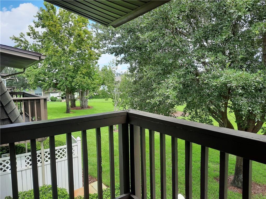 A view from a wooden balcony overlooking a grassy yard with mature trees — 1695 LEE ROAD UNIT B210, WINTER PARK, FL