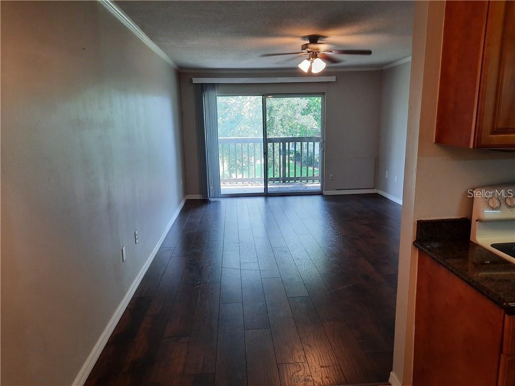An empty living room with dark wood flooring, a ceiling fan, and a sliding glass door — 1695 LEE ROAD UNIT B210, WINTER PARK, FL
