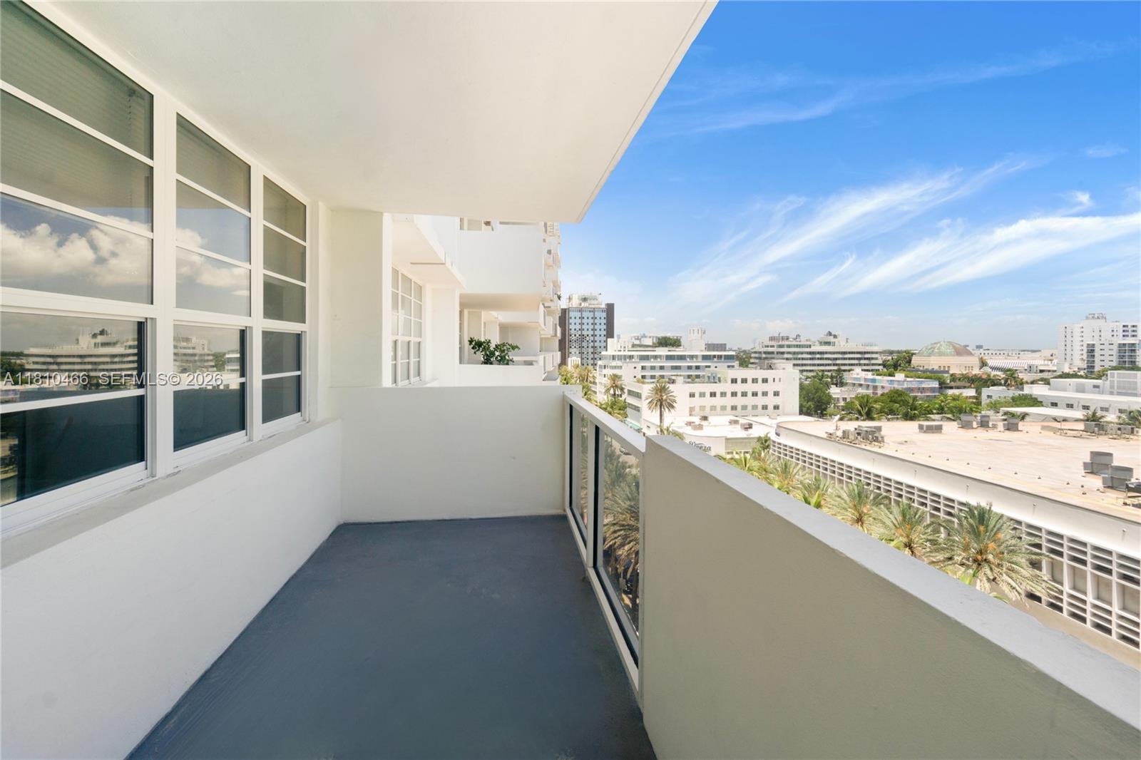 A balcony with a gray floor and glass railing overlooks a city skyline under a sky — 100 Lincoln Rd # 827, Miami Beach FL 33139, MIAMI BEACH, FL