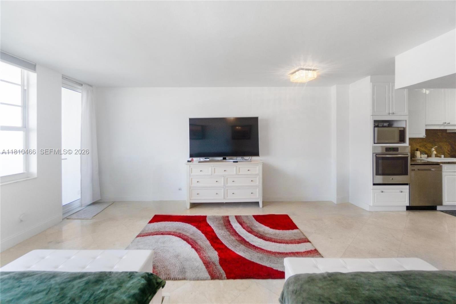 A living room features a white dresser, a television, and a red patterned area rug — 100 Lincoln Rd # 827, Miami Beach FL 33139, MIAMI BEACH, FL