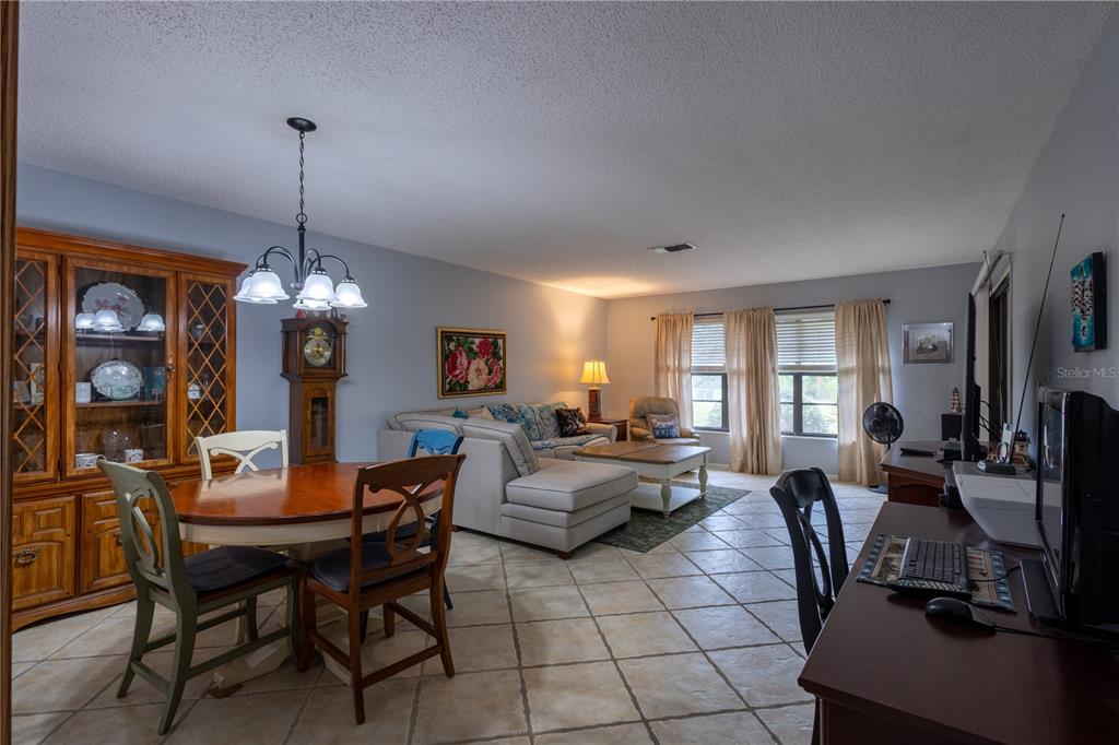 An open-concept living and dining area features tile flooring, a wooden hutch, and neutral walls — 7913 PINEGLEN COURT UNIT 34, SARASOTA, FL