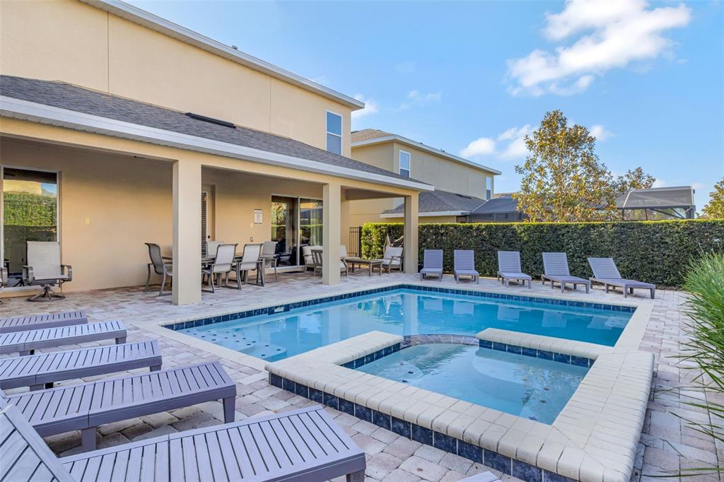 A backyard patio features a swimming pool, a hot tub, and several lounge chairs — 7643 WILMINGTON LOOP, KISSIMMEE, FL