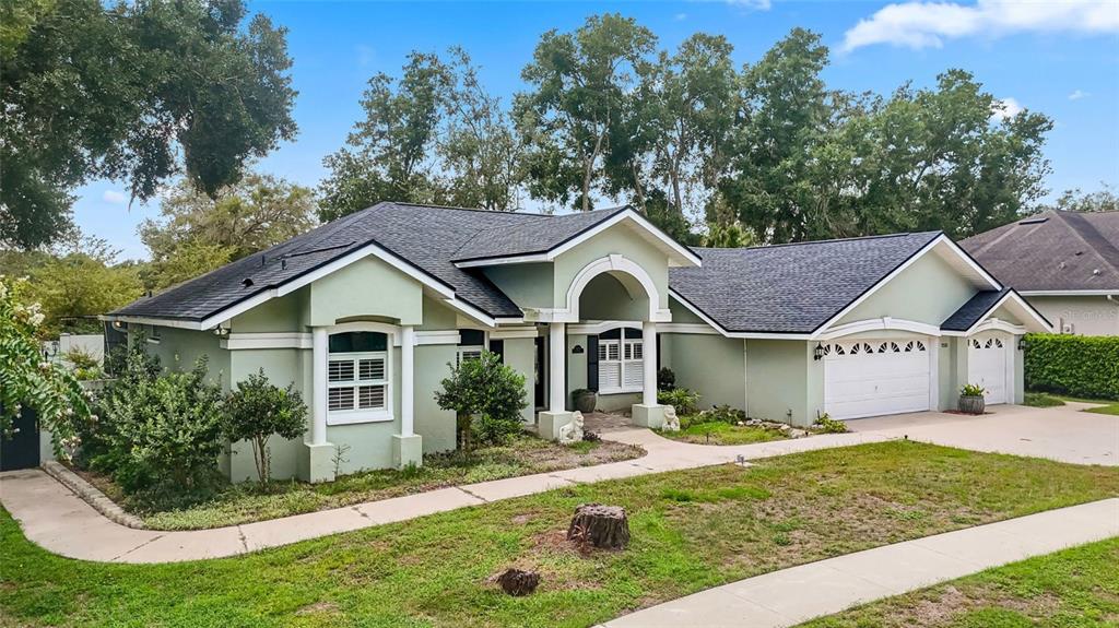 A light green single-story house with a dark shingled roof and a three-car garage — 7225 RIVER FOREST LANE, TEMPLE TERRACE, FL