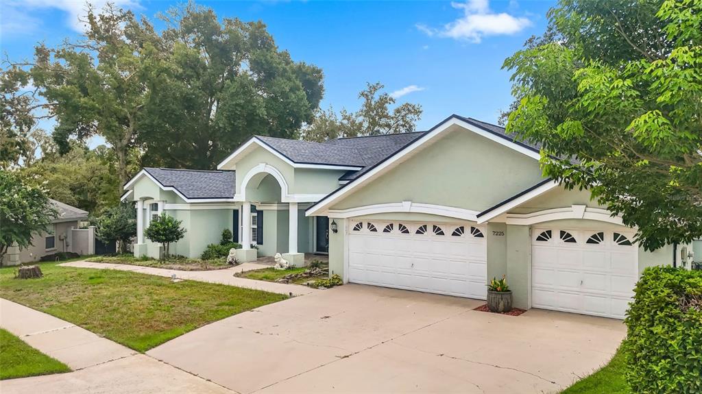 A light green single-story house with a three-car garage and a covered entryway — 7225 RIVER FOREST LANE, TEMPLE TERRACE, FL