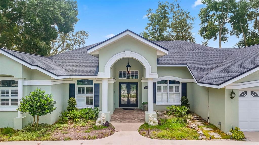 A light green house with a covered entryway, white columns, and a dark shingled roof — 7225 RIVER FOREST LANE, TEMPLE TERRACE, FL