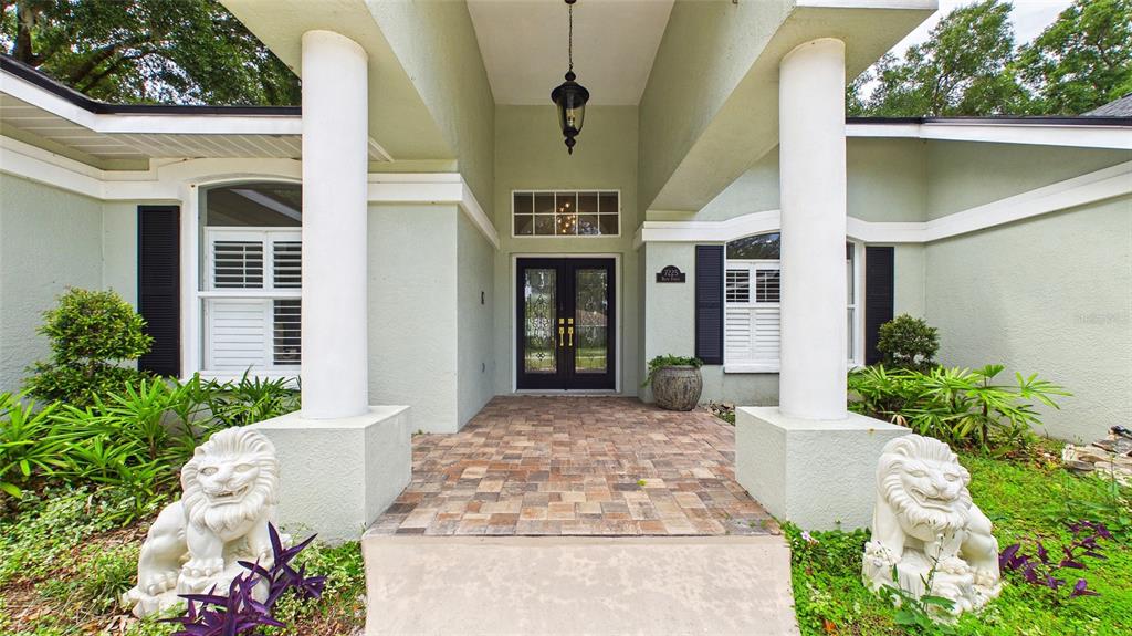 A front entryway features a paved porch, two lion statues, and a double glass door — 7225 RIVER FOREST LANE, TEMPLE TERRACE, FL