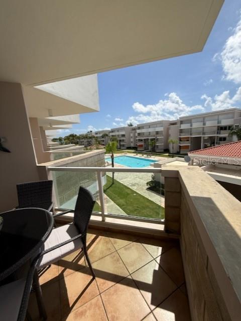 A balcony with patio furniture overlooks a swimming pool and multi-story apartment buildings — Cond. Bosque del Mar EDIFICIO A UNIT H-302, RIO GRANDE, PR