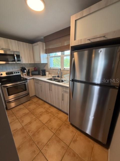 A kitchen with light wood cabinets, stainless steel appliances, and tan tile flooring — Cond. Bosque del Mar EDIFICIO A UNIT H-302, RIO GRANDE, PR
