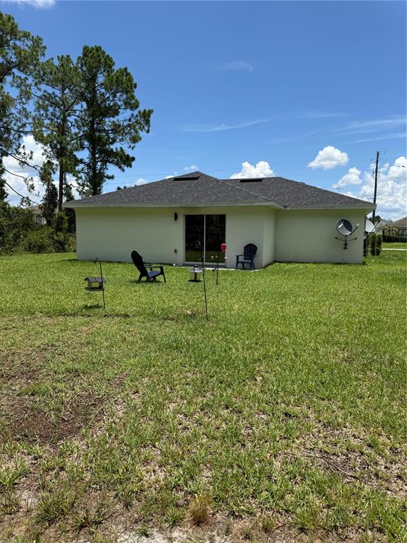 The exterior rear view of a single-story house features a sliding glass door and lawn — 5421 PONCE DE LEON BOULEVARD, SEBRING, FL