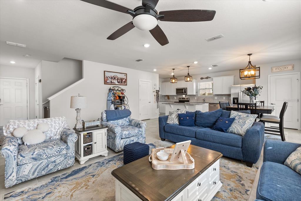 A living room with blue furniture and a kitchen in the background — 2224 CANOPY TERRACE BOULEVARD, DELAND, FL