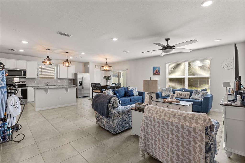 An open-concept kitchen and living area features tile flooring, white cabinetry, and blue furniture — 2224 CANOPY TERRACE BOULEVARD, DELAND, FL