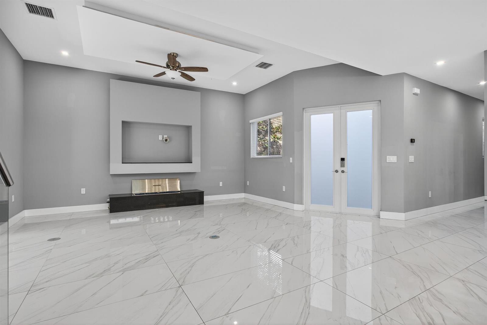 A living room features gray walls, white marble-look tile floors, a fireplace, and double doors — 69 S Cortez Drive # 69, Margate FL 33068, MARGATE, FL