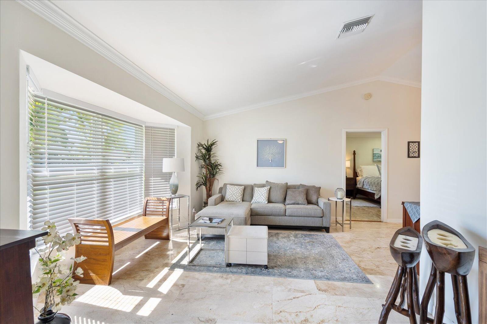 A living room with a grey sectional sofa, tile flooring, and a large bay window — 13889 Geranium Place, Wellington FL 33414, WELLINGTON, FL