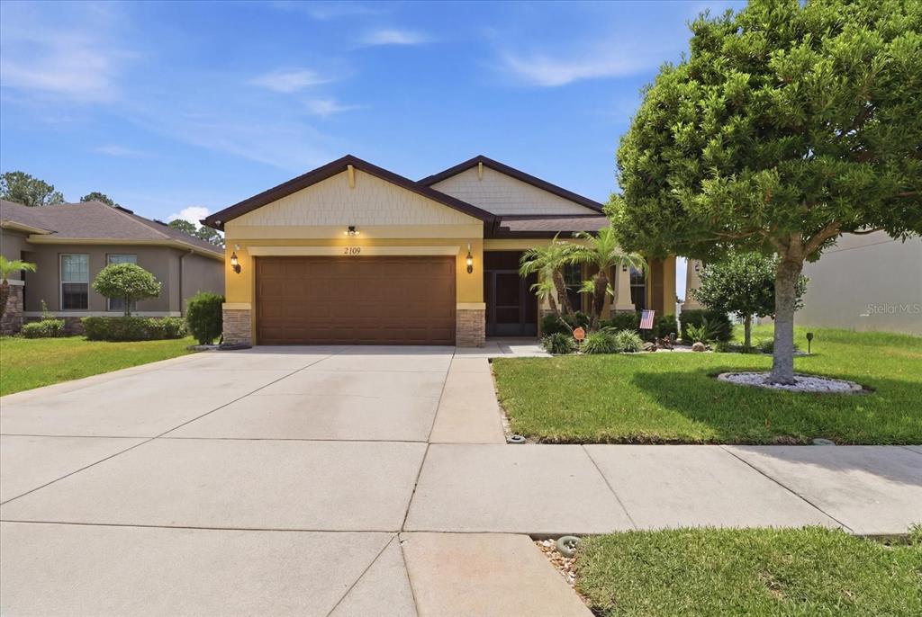 A single-story house with a two-car garage, yellow siding, and a concrete driveway — 2109 TRILLIUM BOULEVARD, BROOKSVILLE, FL