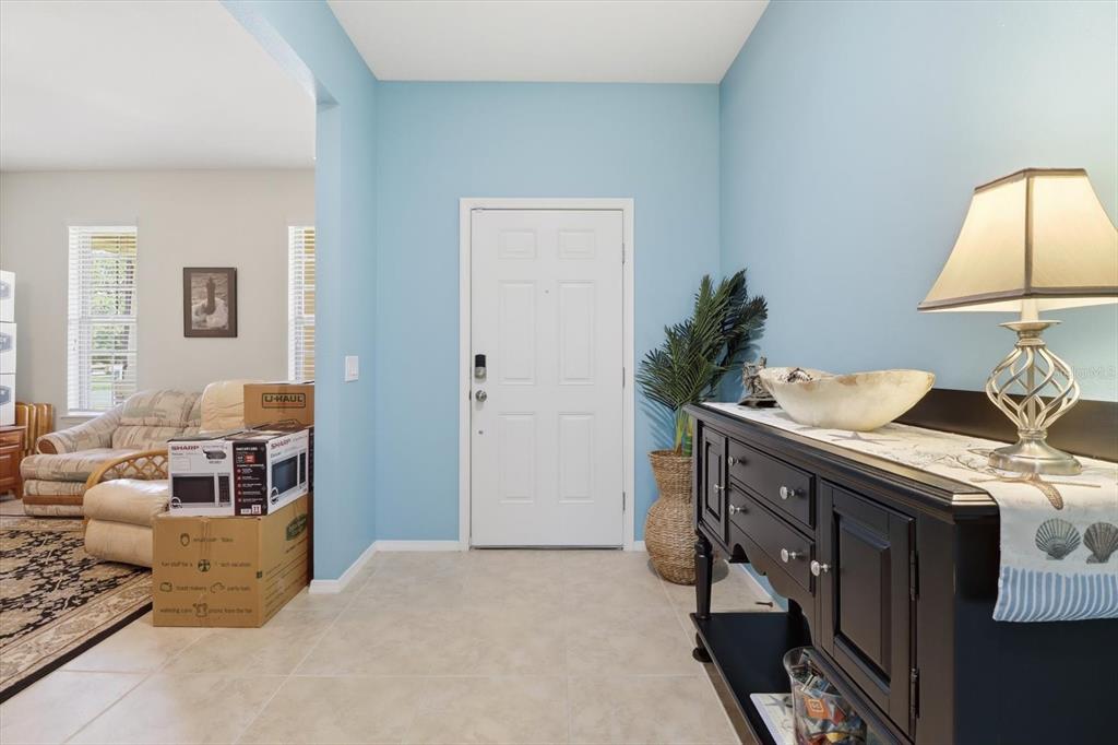 An entryway features light blue walls, tile flooring, a white front door, and a black console — 2109 TRILLIUM BOULEVARD, BROOKSVILLE, FL