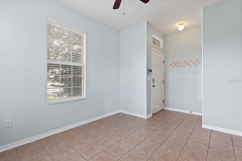 A room with light blue walls, tile flooring, a window with blinds, and an entry door — 6981 TOWERING SPRUCE DRIVE, RIVERVIEW, FL