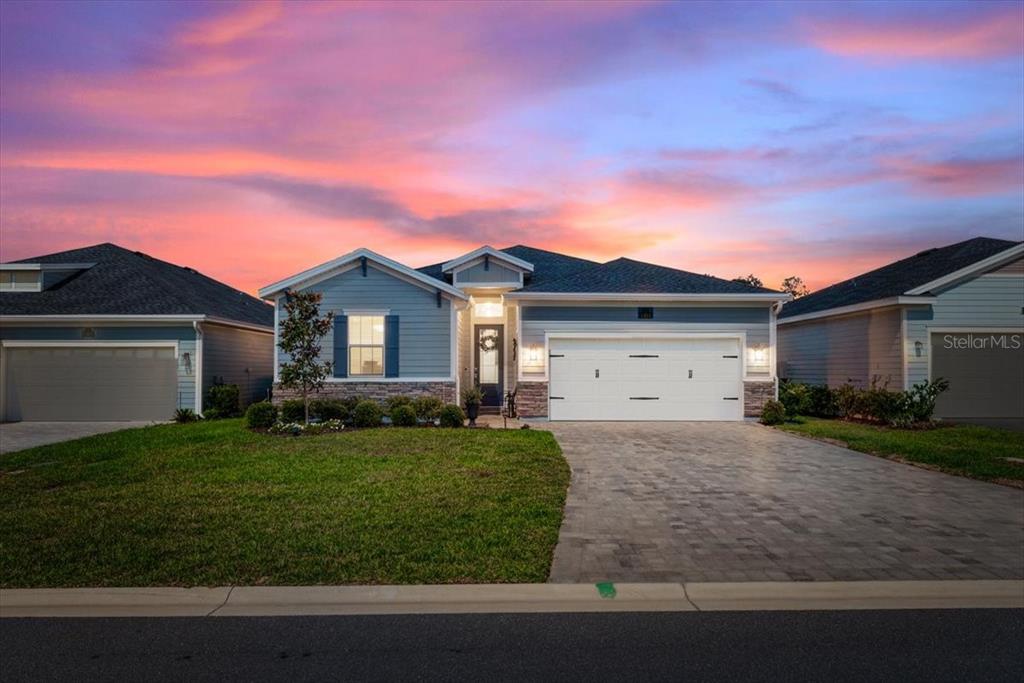 A single-story house with blue siding, a stone facade, and a paved driveway at sunset — 1401 STILLWATER BOULEVARD, ST JOHNS, FL