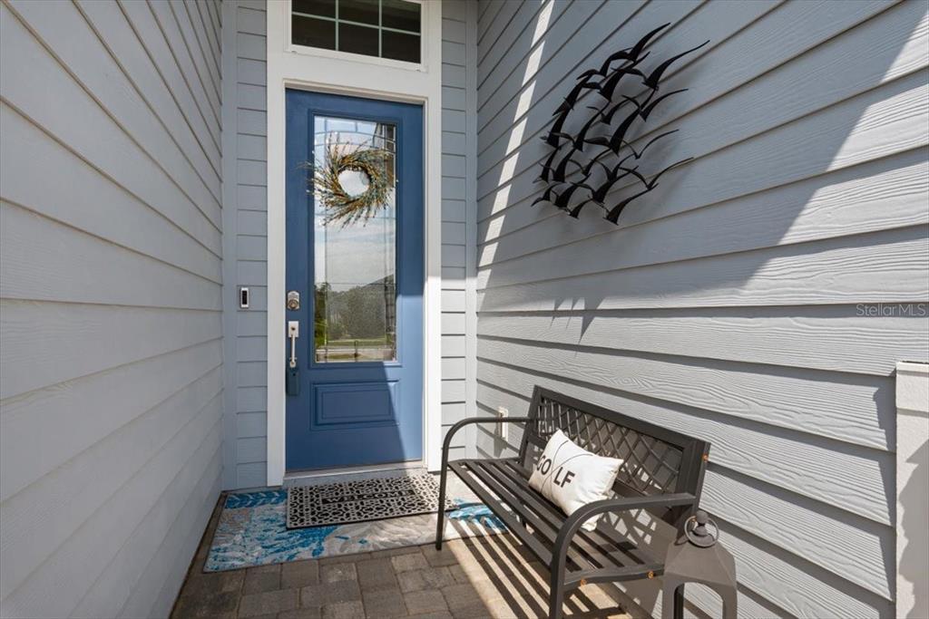 A blue front door with a wreath and a metal bench on a porch — 1401 STILLWATER BOULEVARD, ST JOHNS, FL