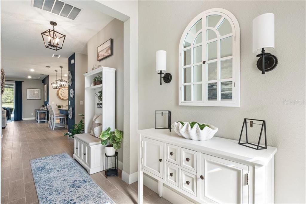 A bright entryway features a white console table, wall sconces, and a built-in hall tree — 1401 STILLWATER BOULEVARD, ST JOHNS, FL