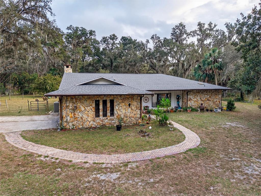 A single-story house with a stone facade and a curved brick walkway in a yard — 11795 SW HIGHWAY 484, DUNNELLON, FL