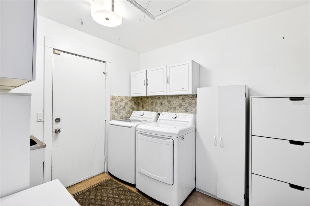 A laundry room features white appliances, wall-mounted cabinets, and a patterned tile backsplash — 11795 SW HIGHWAY 484, DUNNELLON, FL