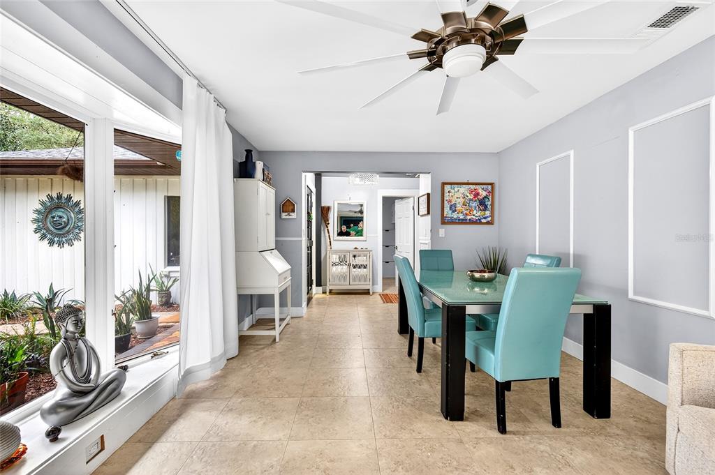 A dining room with a glass-topped table, turquoise chairs, tile flooring, and large windows — 11795 SW HIGHWAY 484, DUNNELLON, FL