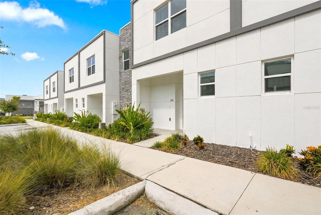 A modern two-story townhouse exterior with white stucco walls, gray trim, and a stone accent — 285 FAMAGUSTA DRIVE, DAVENPORT, FL