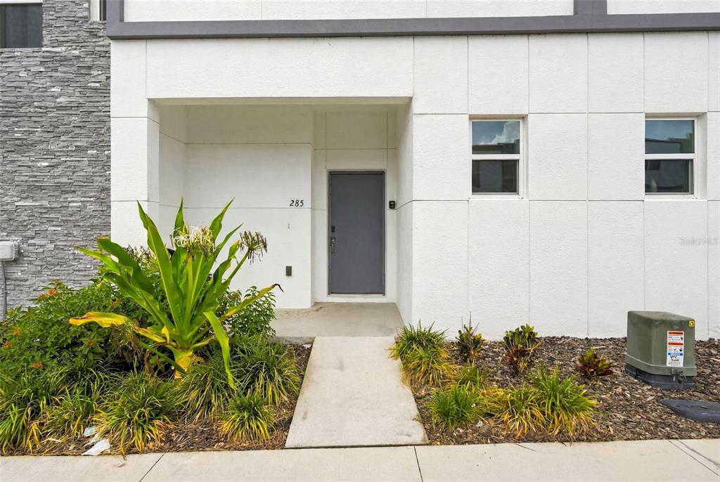 The exterior of a modern townhouse features a white facade, a gray door, and landscaping — 285 FAMAGUSTA DRIVE, DAVENPORT, FL