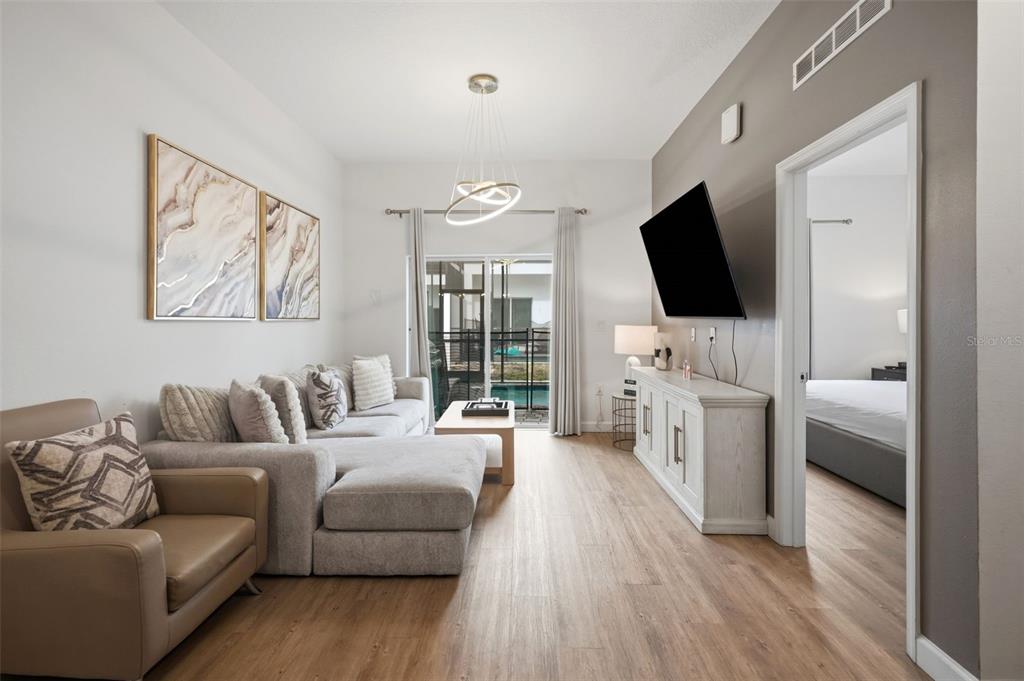 A living room features a sectional sofa, a television on a console, and sliding doors — 285 FAMAGUSTA DRIVE, DAVENPORT, FL
