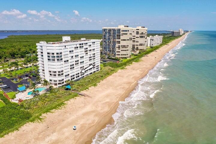 An aerial view shows a white multi-story beachfront condominium building next to a sandy beach — 9600 S Ocean Drive # 306, Jensen Beach FL 34957, JENSEN BEACH, FL