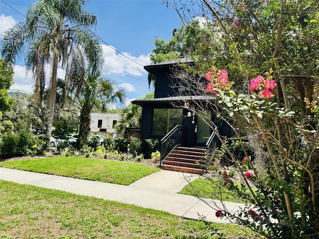 A dark-painted two-story house features a brick front staircase and a palm tree nearby — 516 E JACKSON STREET, ORLANDO, FL