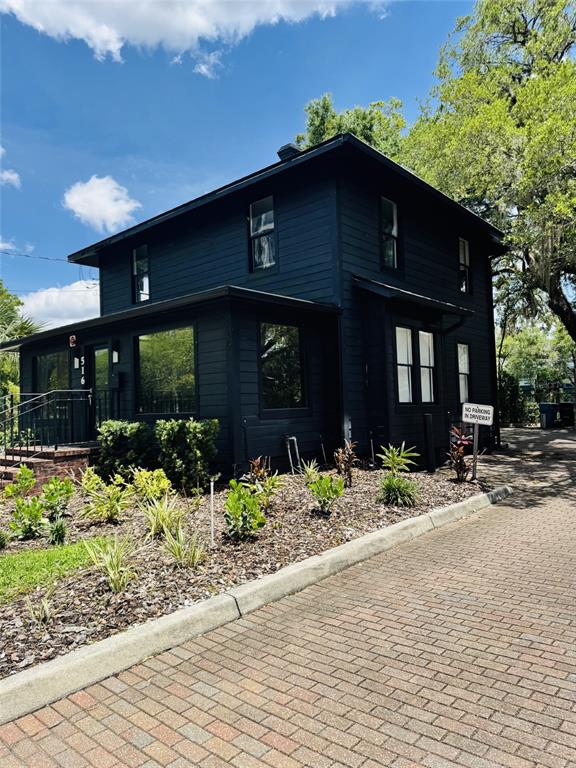 A two-story house with dark siding and a brick driveway on a sunny day — 516 E JACKSON STREET, ORLANDO, FL