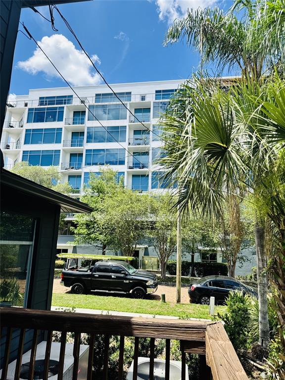 A view from a wooden deck looking toward a modern multi-story apartment building and vehicles — 516 E JACKSON STREET, ORLANDO, FL