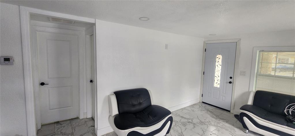 A room with white walls, marble-patterned tile floors, two black and white chairs, and a door — 3004 E DR MARTIN LUTHER KING JR BOULEVARD, TAMPA, FL
