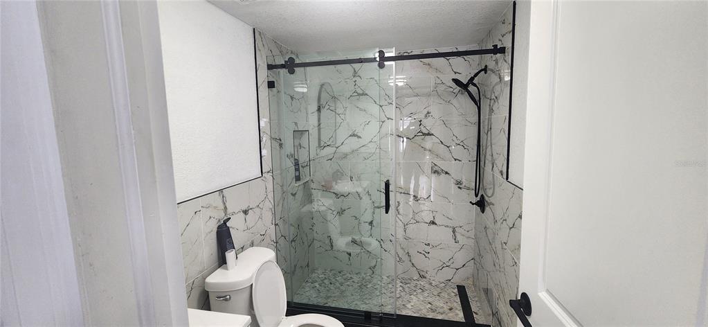 A bathroom features a walk-in shower with marble-patterned tile and a sliding glass door — 3004 E DR MARTIN LUTHER KING JR BOULEVARD, TAMPA, FL