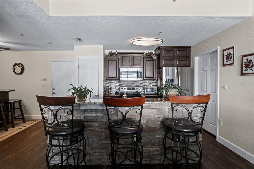 A kitchen features dark wood cabinets, granite countertops, a stone-faced island, and three bar stools — 700 S HARBOUR ISLAND BOULEVARD UNIT 532, TAMPA, FL