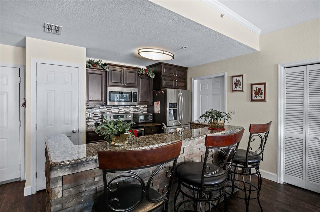 A kitchen features dark wood cabinets, granite countertops, a stone-faced breakfast bar, and three stools — 700 S HARBOUR ISLAND BOULEVARD UNIT 532, TAMPA, FL